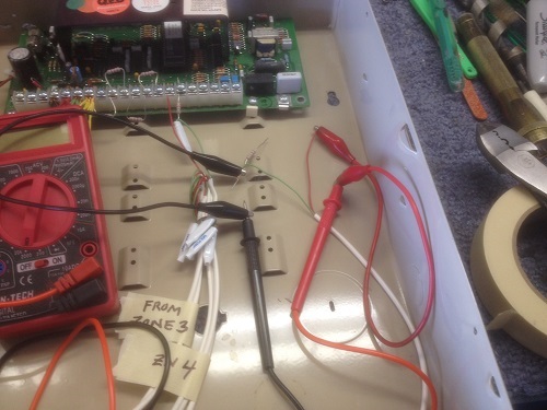 DMM probes connected to alarm panel wiring using alligator clips