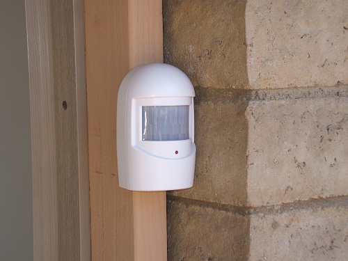 Driveway alert sensor installed at side of garage door, looking along driveway